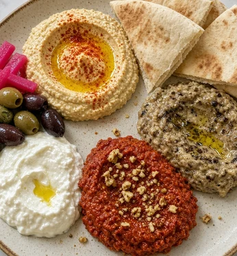 Mezze plate with hummus, mutabal, muhammara and garlic dip, olives, pickled turnip and pita