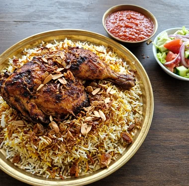 Yemeni chicken mandi: roasted chicken on yellow and white mandi rice with fried onions, almonds and raisins, with dakkous sauce and salad